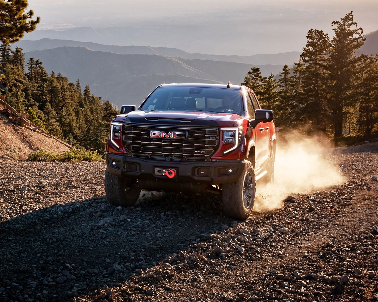 Front 3/4 shot of the 2025 GMC Sierra 1500 kicking up dirt on road.